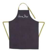 Load image into Gallery viewer, The soft, grey sand washed cotton linen of the Annie Sloan Apron, with contrasting green tie backs, makes for both comfortable and practical wear. The large double front pocket is the ideal place to store tin openers, mixing sticks and brushes, and the adjustable neck length means it will suit any height of painter. With the iconic Annie Sloan signature emblazoned in silver.
