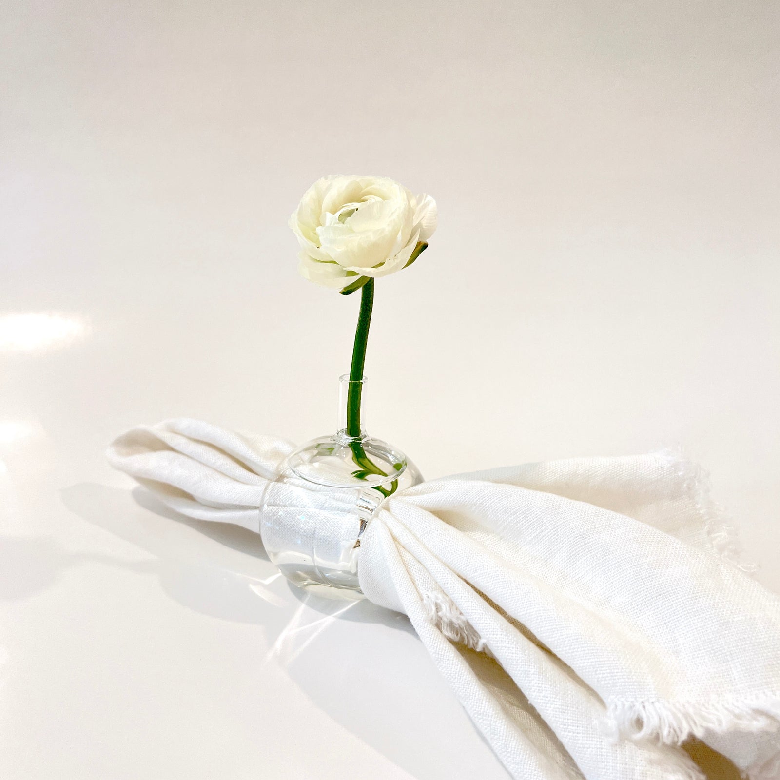 Our beautifully refined hand-blown glass vase napkin holders are perfect for every occasion. With the option to add a beautiful flower, your dining table will definitely be the one to stand out.  2" W x 2" D x 3 1/2"   ***Sold individually