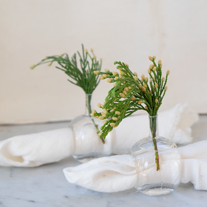 Our beautifully refined hand-blown glass vase napkin holders are perfect for every occasion. With the option to add a beautiful flower, your dining table will definitely be the one to stand out.  2" W x 2" D x 3 1/2"   ***Sold individually